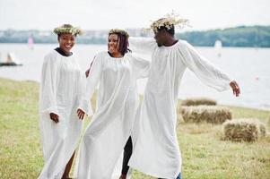 três amigos afro-americanos em capas brancas e grinalda se divertindo juntos. foto