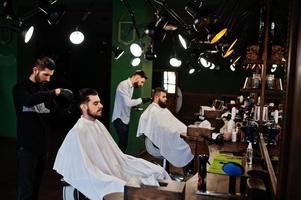 homem barbudo bonito na barbearia, barbeiro no trabalho. foto