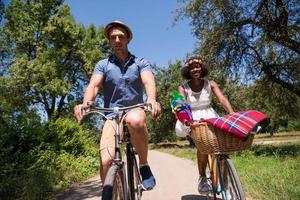 jovem casal multiétnico dando um passeio de bicicleta na natureza foto