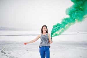 jovem com bomba de fumaça de cor verde na mão em dia de inverno. foto