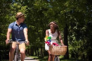 jovem casal multiétnico dando um passeio de bicicleta na natureza foto