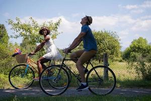 jovem casal multiétnico dando um passeio de bicicleta na natureza foto