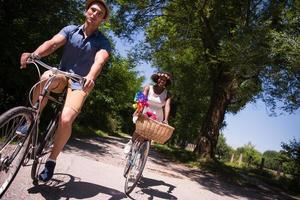 jovem casal multiétnico dando um passeio de bicicleta na natureza foto