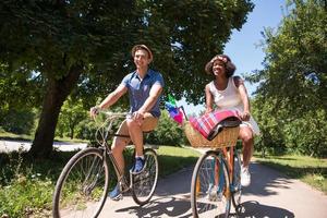 jovem casal multiétnico dando um passeio de bicicleta na natureza foto