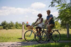 jovem casal multiétnico dando um passeio de bicicleta na natureza foto