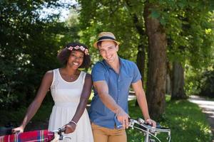 jovem casal multiétnico dando um passeio de bicicleta na natureza foto