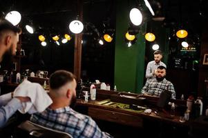 homem barbudo bonito na barbearia, barbeiro no trabalho. foto