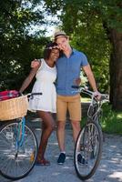 jovem casal multiétnico dando um passeio de bicicleta na natureza foto