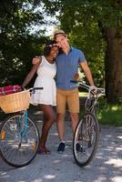 jovem casal multiétnico dando um passeio de bicicleta na natureza foto