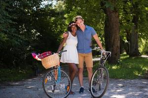 jovem casal multiétnico dando um passeio de bicicleta na natureza foto