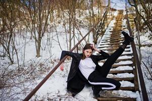 modelo morena de pernas longas na moda no manto preto longo posou ao ar livre no dia de inverno. foto