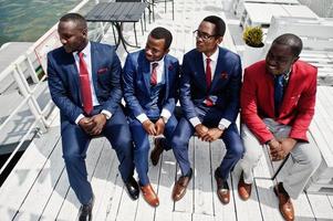 grupo de quatro afro-americanos feliz sucesso mans no terno. rico empresário negro sentado em cadeiras. foto