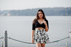menina bonita modelo latino do Equador usar tops pretos e saia posada contra o lago. foto