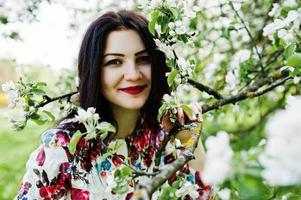 retrato de primavera de menina morena no jardim de flor verde. foto