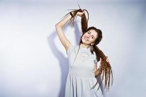 ensaio de estúdio de menina de vestido cinza com tranças dreads em fundo branco. foto