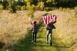 dois irmãos correndo com a bandeira dos eua. feriado americano. orgulho de ser filhos da pátria. foto