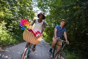 jovem casal multiétnico dando um passeio de bicicleta na natureza foto