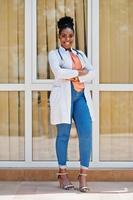 médico americano africano feminino no jaleco com estetoscópio posado ao ar livre contra a clínica. foto