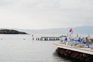 cais com espreguiçadeiras. paisagem cênica com ilhas de montanha e lagoa azul no mar egeu. cenário exótico. marco popular, famoso destino de bodrum, turquia. foto