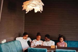 amigos africanos felizes sentados e conversando no café. grupo de negros reunidos em restaurante. foto