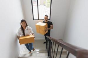 um casal com uma caixa grande em sua nova casa. carregando coisas para uma nova casa foto