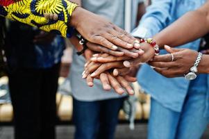 grupo de cinco estudantes universitários africanos passando tempo juntos no campus no pátio da universidade. amigos negros afro estudando. tema educação. mãos nas mãos. foto