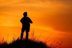silhueta de soldado militar ou oficial com armas ao pôr do sol foto