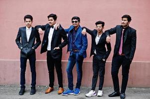grupo de 5 estudantes indianos de terno posou ao ar livre contra a parede rosa. foto