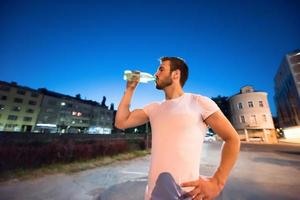 homem bebendo água após a sessão de corrida foto