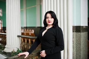 menina morena de vestido preto na estação ferroviária interior. foto