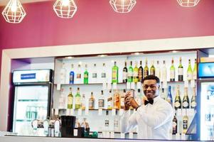 barman americano africano no bar com shaker. preparação de bebidas alcoólicas. foto