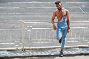 homem de torso nu afro-americano sexy bonito no macacão jeans posou no estádio. retrato de homem negro na moda. foto