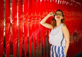 mulher ruiva atraente em óculos posando contra um fundo vermelho. foto