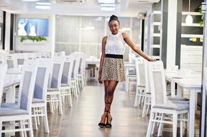 encantadora mulher afro-americana em saia de leopardo posando no restaurante. foto