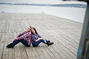 casal elegante usa camisa quadriculada apaixonada juntos sentados no cais. foto