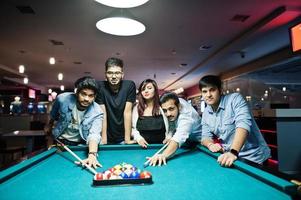 grupo de amigos asiáticos elegantes usam jeans jogando bilhar no bar. foto