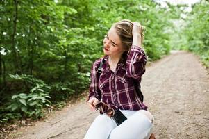retrato de uma linda loira na camisa tartan, sentado no chão na zona rural. foto
