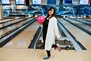 elegante mulher asiática em pé na pista de boliche com bola na mão. foto