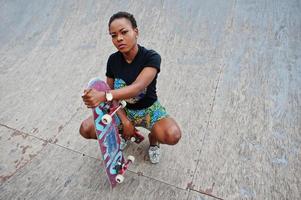 jovem afro-americana posou com skate no skate park. foto