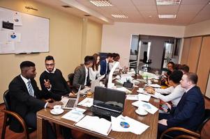 equipe de negócios multirracial abordando a reunião em torno da mesa da diretoria. foto