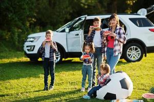 família passar tempo juntos. quatro filhos com mãe comem melancia ao ar livre. foto