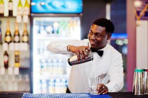 barman americano africano no bar com shaker. preparação de bebidas alcoólicas. foto