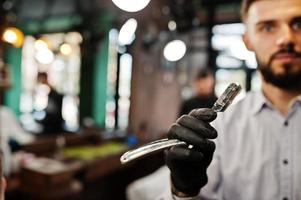 homem barbudo bonito na barbearia, barbeiro no trabalho. foto