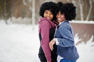 duas mulheres afro-americanas de cabelo encaracolado usam suéteres posados no dia de inverno. foto