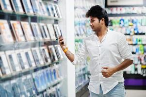 comprador de cliente homem indiano na loja de telefonia móvel escolhe seu novo smartphone. conceito de povos e tecnologias do sul da Ásia. loja de celulares. foto