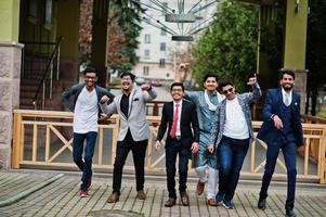 grupo de seis homens indianos do sul da Ásia em roupas tradicionais, casuais e de negócios andando dançando e se divertindo juntos. foto