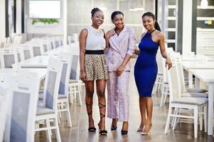 três mulheres africanas de vestido posando no restaurante. foto