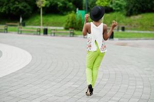 incrível mulher modelo americano africano em calças verdes e chapéu preto posou no parque. foto