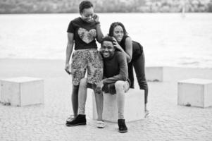 três amigos afro-americanos sentados em cubos de pedra ao ar livre. foto