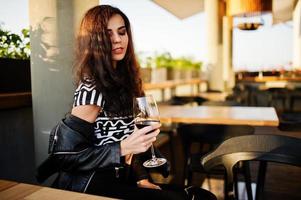 jovem mulher encaracolada desfrutando de seu vinho em um bar. foto